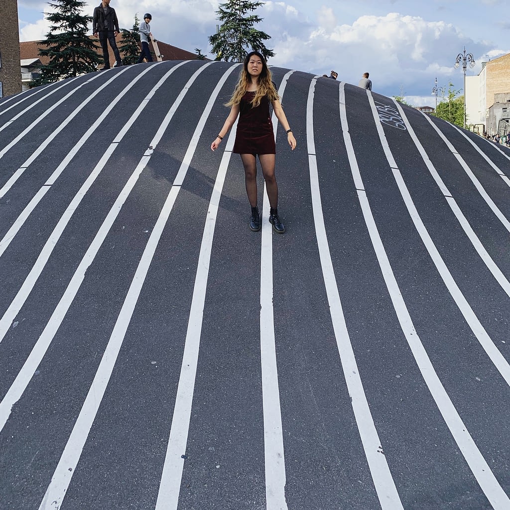 Girl standing on hill made of pavement with vertical white lines