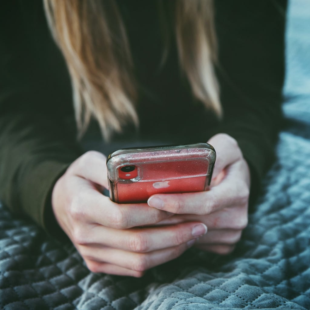 Close up of hands holding red iPhone