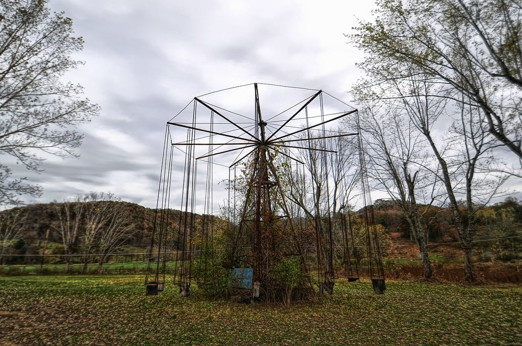 Old abandoned rusty swing ride at amusement park