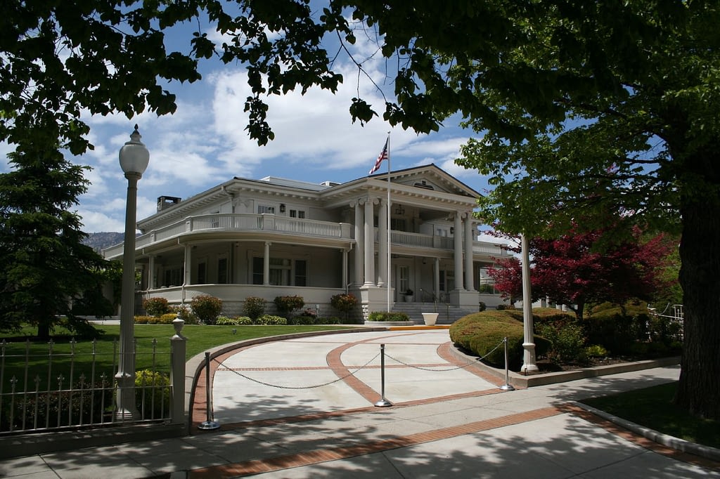 White mansion and circular driveway, framed by trees