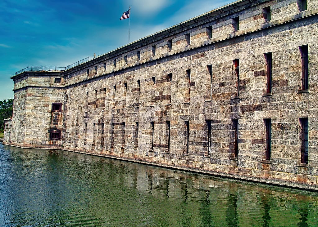 Fort with weathered bricks surrounded by a moat, American flag on top