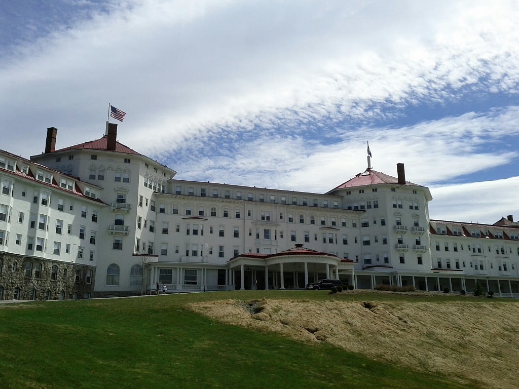 Large white building with red roof on top of a hill