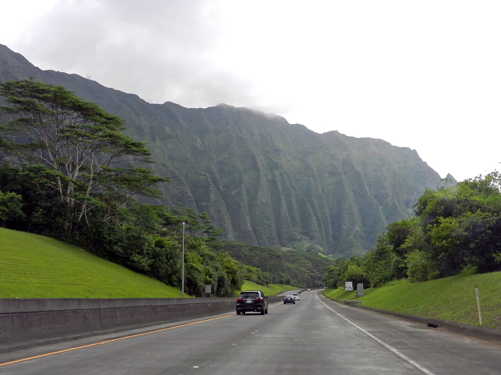 Highway with mountain ahead and green grass and trees on both sides