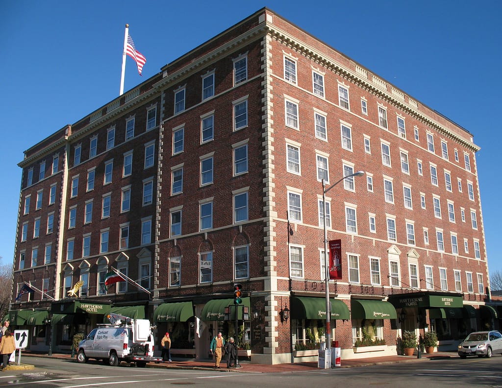 Large brick building with American flag on top, green awnings